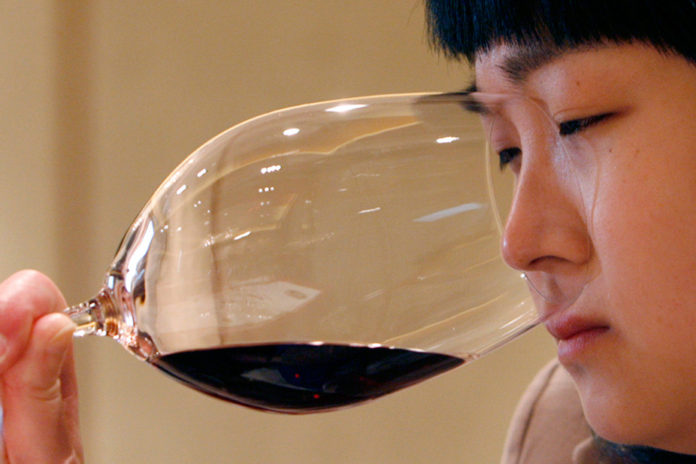 A woman sniffs a glass of wine during a tasting event in Beijing. Reuters