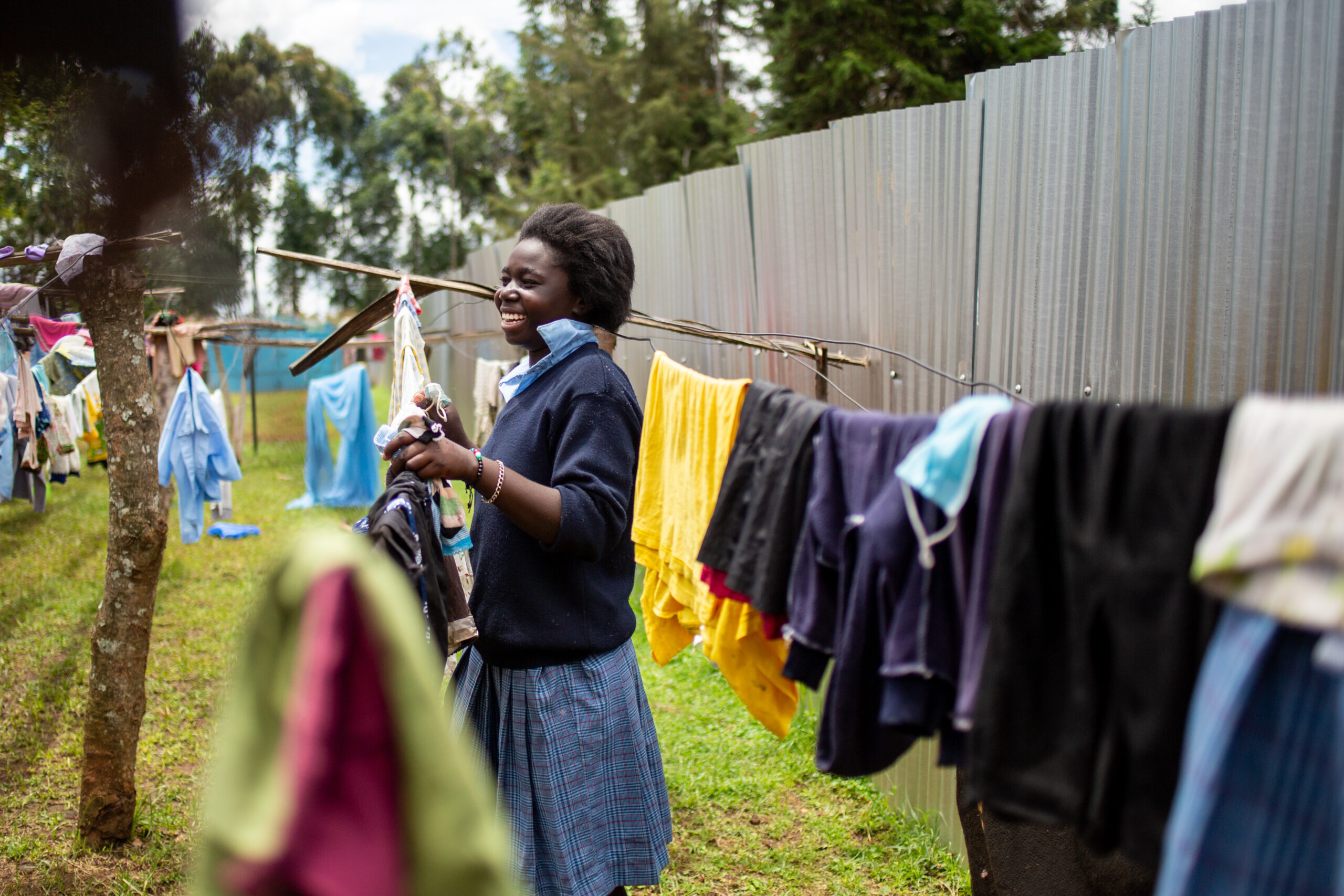A young woman of the Neema Project sets clothes out to dry
