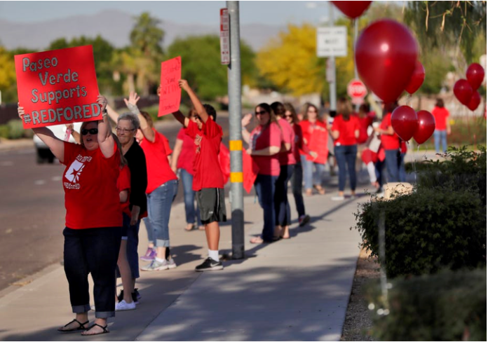 Teachers and students wave to motorists in Peoria, Ariz. AP Photo/Matt York
