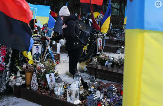A Ukrainian woman touches the grave of her husband, a soldier killed by Russian troops in August 2022. Sean Gallup/Getty Images