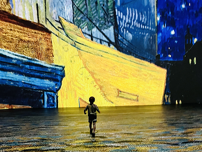 A child's silhouette against the backdrop of the Beyond Van Gogh exhibit in Sarasota