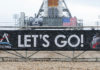 A banner signed by NASA employees and contractors outside Launch Complex 39B, where NASA’s Artemis II rocket is visible in the background. NASA/Joel Kowsky, CC BY-NC-ND