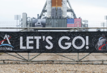 A banner signed by NASA employees and contractors outside Launch Complex 39B, where NASA’s Artemis II rocket is visible in the background. NASA/Joel Kowsky, CC BY-NC-ND