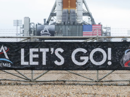 A banner signed by NASA employees and contractors outside Launch Complex 39B, where NASA’s Artemis II rocket is visible in the background. NASA/Joel Kowsky, CC BY-NC-ND