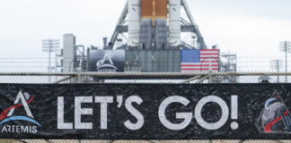 A banner signed by NASA employees and contractors outside Launch Complex 39B, where NASA’s Artemis II rocket is visible in the background. NASA/Joel Kowsky, CC BY-NC-ND