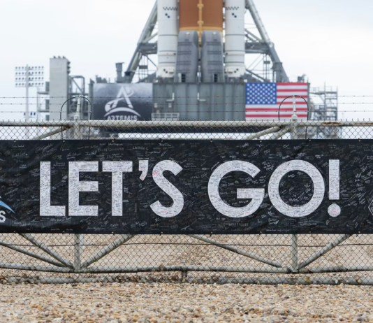 A banner signed by NASA employees and contractors outside Launch Complex 39B, where NASA’s Artemis II rocket is visible in the background. NASA/Joel Kowsky, CC BY-NC-ND
